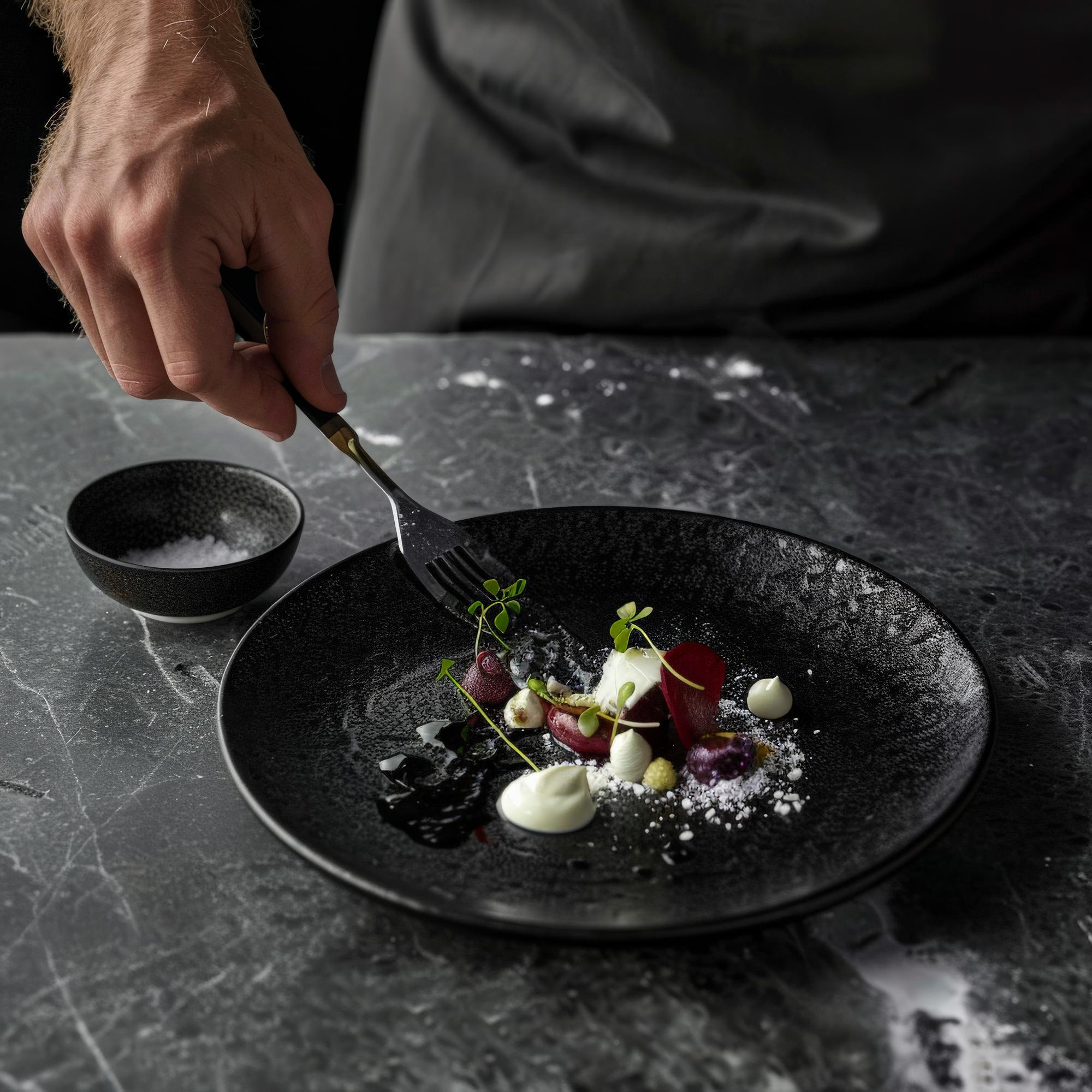 Chef garnishing a plated gourmet dish in an elegant kitchen